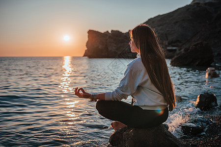 日落时分 身着运动服 头戴波西米亚风格手镯的长发年轻女子在海边的瑜伽垫上在户外练习 女性瑜伽健身程序 健康的生活方式 和谐与冥想图片