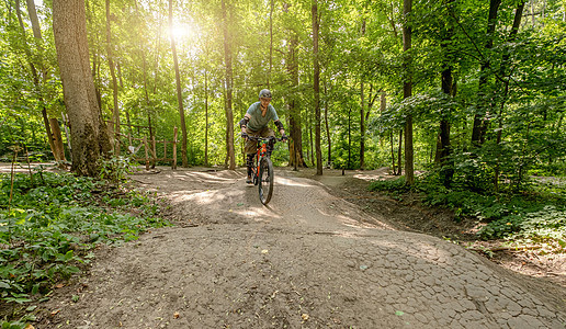 男子在森林道路上骑自行车锻炼自然阳光地面公园头盔环境闲暇骑术娱乐图片