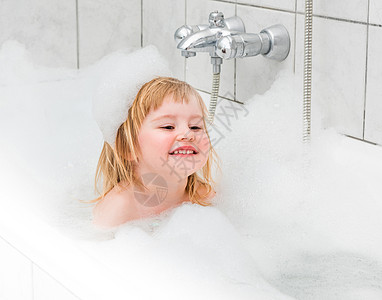 长着可爱的两岁小孩在浴池里用泡沫洗澡孩子女性眼睛浴室乐趣气泡童年生活肥皂女孩图片