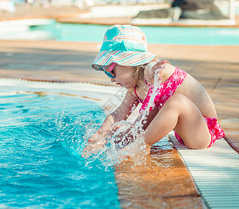 坐在泳池旁边的小女孩微笑享受童年乐趣水池幸福青年孩子太阳帽游泳图片