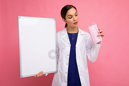 身穿白色医用大衣的女医生拿着空白板 上面有文本的复制空间和背景隔离的防护面罩 Covid概念木板医疗黑发预防外套女士护士卫生疾病图片