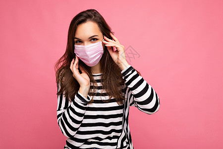 戴着抗病毒防护面具的年轻女性 以防止他人感染粉红色背景下的19 和 SARS cov 2 感染面膜药品面具深色青年黑发防护安全医背景图片
