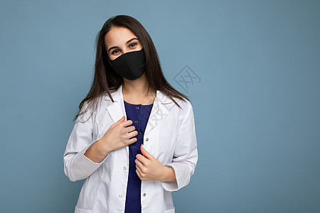 身戴病毒防护面具 面部面对冠状病毒和蓝底孤立的白色医疗大衣的妇女图片