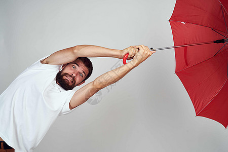 红伞男子手持保护伞 免受雨雨雨的侵袭男人微笑人士头发天气成人棕色商务套装快乐图片