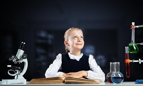 微笑的小女孩坐在书本开着的桌子上孩子课堂文学百科童年学生科学家孩子们瞳孔女学生图片