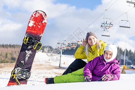 母亲和女儿带着雪板在雪中玩耍高山青少年孩子假期滑雪板季节旅行女性乐趣缆车图片