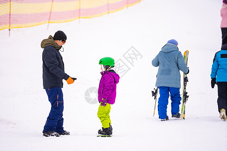 教官在雪坡向雪板上教导一名儿童行动训练滑雪板女孩活动教学晴天闲暇父亲自由图片
