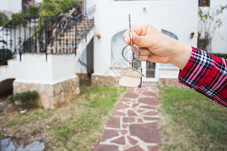 房地产和财产概念  手拿着房子钥匙在新家前的房子形钥匙链上戒指贷款交换大厦商务男人公寓顾客建筑物房东图片