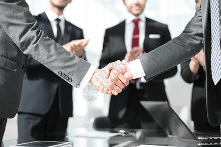 商务握手办公室财务伙伴的握手之握合同桌子团队同事经理电脑工作成人职业桌面背景