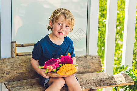龙果和芒果 在男孩的手中异国热带甜点亚麻叶子食物水果紫色温泉浆果图片