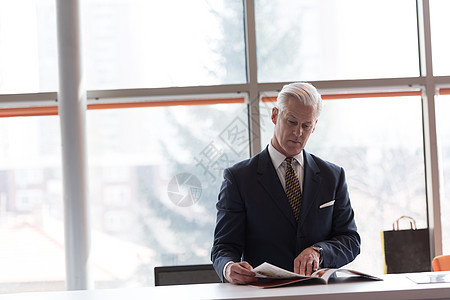 高级商业人士阅读杂志男性休息报纸男人经理出版物审查蓝色头发办公室图片