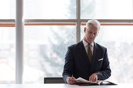 高级商业人士阅读杂志商务报纸套装审查男人休息成人男性经理出版物图片
