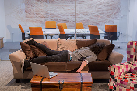 男人睡在有创意的办公室的沙发上笔记本说谎电脑员工职业职场经理成功管理人员商务图片