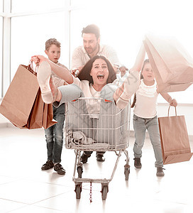 快乐的家庭去购物 在超市中妈妈乐趣父母微笑父亲女性零售大车孩子市场图片