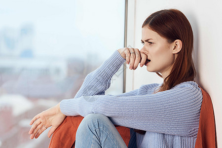 带着悲伤的表情的女人坐在窗边 用一个格子坐着窗户女孩女性闲暇杯子假期咖啡思维女士图片