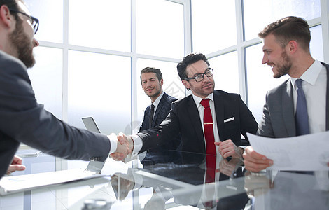 在谈判桌上与商业界人士进行握手交流顾问办公室男性合作职业生意人文档合同商务会议图片