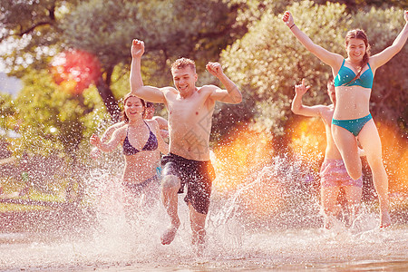 一群快乐的朋友在河边玩乐女孩跳跃旅行男人朋友们派对女士青年学生假期图片