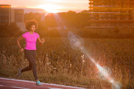 一名非洲裔美国年轻女子在户外慢跑衣服跑步女士公园运动赛跑者太阳运动装身体成人图片