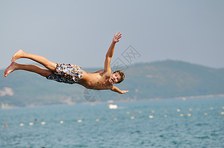 男孩跳海潜水海滨海滩波浪闲暇海岸男人天空地平线男性图片