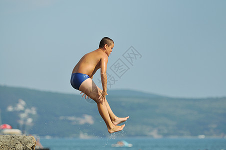 男孩跳海乐趣假期空气海岸自由孩子技巧男人喜悦蓝色图片