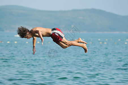 男孩跳海海岸海滨波浪天空闲暇技巧活力自由地平线海洋图片