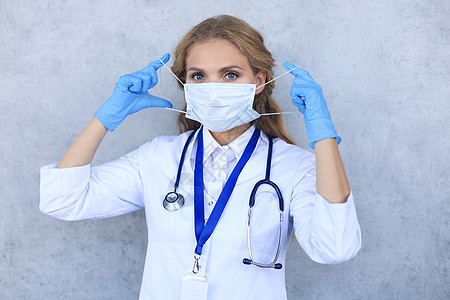 戴医疗面具的女医生 带着听诊器 看着在灰色背景上隔绝的照相机职业安全工作专家实验室工人女性诊所护士女士图片