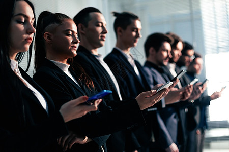 拥有智能手机的青年商务人士站成一排屏幕工人公司员工人士男性同事技术走廊生意图片