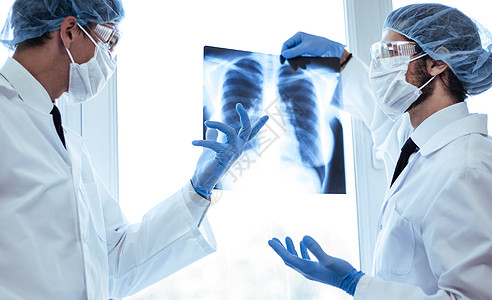 近距离接近 戴防护面罩的科学家在看肺部X光片技术症状成人测试疾病从业者职业讨论眼镜x光图片