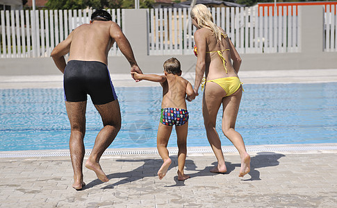 快乐的年轻家庭 在游泳池玩得开心喜悦假期幸福儿子母亲男人女孩乐趣爸爸蓝色图片