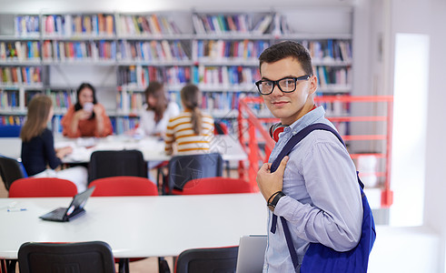 学生使用笔记本 纸顶和学校图书馆书架阳光知识办公室成人书柜微笑工作家庭作业电脑图片