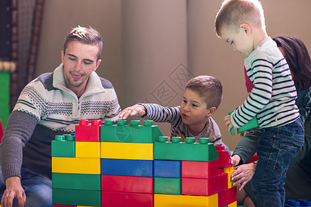 一起玩青少年家长和孩子们在儿童游戏室玩乐妈妈父母女士闲暇喜悦家庭孩子微笑享受母亲背景