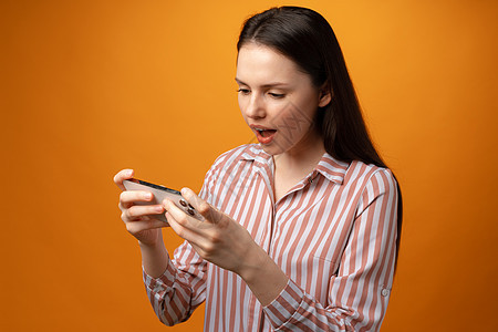 以黄色背景使用智能手机的年轻女性惊讶之春技术学生微笑女士电话乐趣情绪成人青少年水平图片