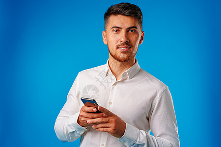 穿白衬衫的年轻人用他的智能手机快乐男人消息成人男性工作室图片