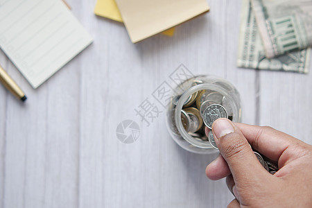 年轻男子在白色的罐子里存着硬币d退休贷款预算男人财富手指经济金融投资银行业图片