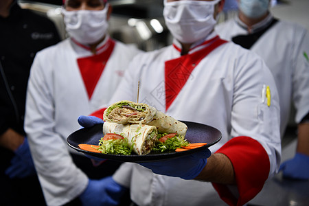 厨师戴口罩在冠状病毒新常态概念下 一群厨师戴着防护医用口罩和手套站在餐厅的厨房里卫生男性混血工作团体餐饮成人保健帽子烹饪背景