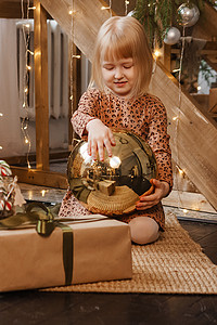 一个金发女孩坐在 斯堪的纳维亚内地的一个木楼梯旁边 装饰着圣诞孩子寒假幸福裙子彩灯衣冠婴儿家居硬木图片