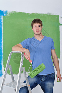 英俊的青年男子用彩色漆白白墙房间职业维修工人刷子工作装修工匠微笑工具图片