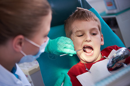 医生关心病人做牙科手术的年轻男孩凹痕病人空腔婴儿工具程序治疗口腔科乐器诊所背景