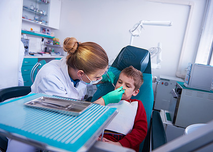 检查牙齿的男孩做牙科手术的年轻男孩程序女性牙医口腔科婴儿治愈保健诊所办公室乐器背景