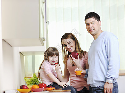 厨房中幸福的年轻家庭孩子们沙拉房子女士家具橙子食物午餐果汁生活图片