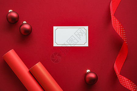 假日品牌标识设计和圣诞平板概念 红色纸背景上的白色空白名片和圣诞装饰品作为平躺模型平铺服务包装婚礼小样卡片横幅会员奢华贵宾图片