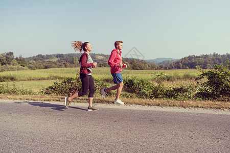 在乡村公路上慢跑的年轻夫妇国家运动装森林训练慢跑者运动员跑步女孩运动自由图片