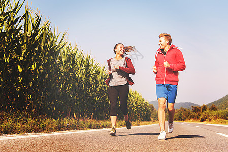 在乡村公路上慢跑的年轻夫妇运动冒险自由阳光男人女孩女士锻炼训练运动员图片