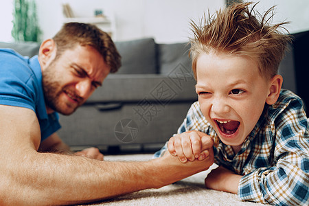 摔跤吧爸爸父亲和儿子在家里地毯上摔跤背景
