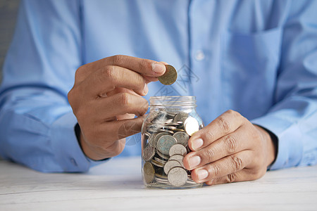 年轻男子在白色的罐子里存着硬币d经济预算贷款男人投资银行业手指退休财富金融图片
