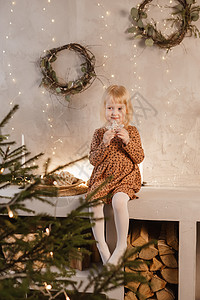 一个女孩在圣诞节前夕在一个为新年节日装饰的美丽房子里玩耍 斯堪的纳维亚式的内地有活林树和木质楼梯硬木寒假衣冠幸福礼物彩灯圣诞礼物图片
