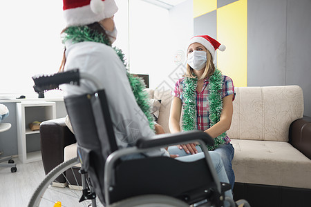 探访住院室朋友 轮轮椅亲属 面罩以保护的家属风格家庭帽子预防沙发女性好朋友药品闲暇房间图片