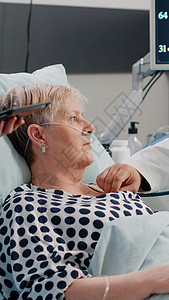 医生关心病人医疗队对床上的老年病人进行体检检查背景