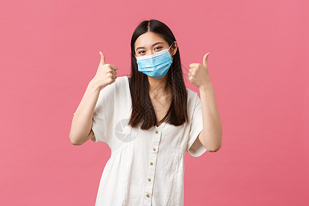 Covid-19 社会距离 病毒和生活方式概念 乐观的亚洲女性穿着白色连衣裙和医用口罩 在冠状病毒期间保持安全 竖起大拇指图片