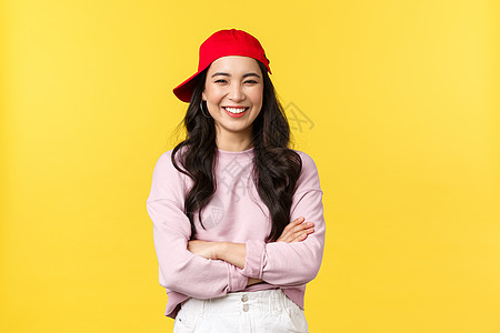 欢乐快乐的亚洲女性笑笑 横跨胸前 在黄色背景上穿着时装红帽看起来酷酷 (YLAKHING)图片